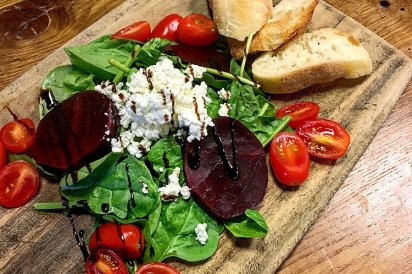 Beet and goat cheese salad served on a wooden cutting board.